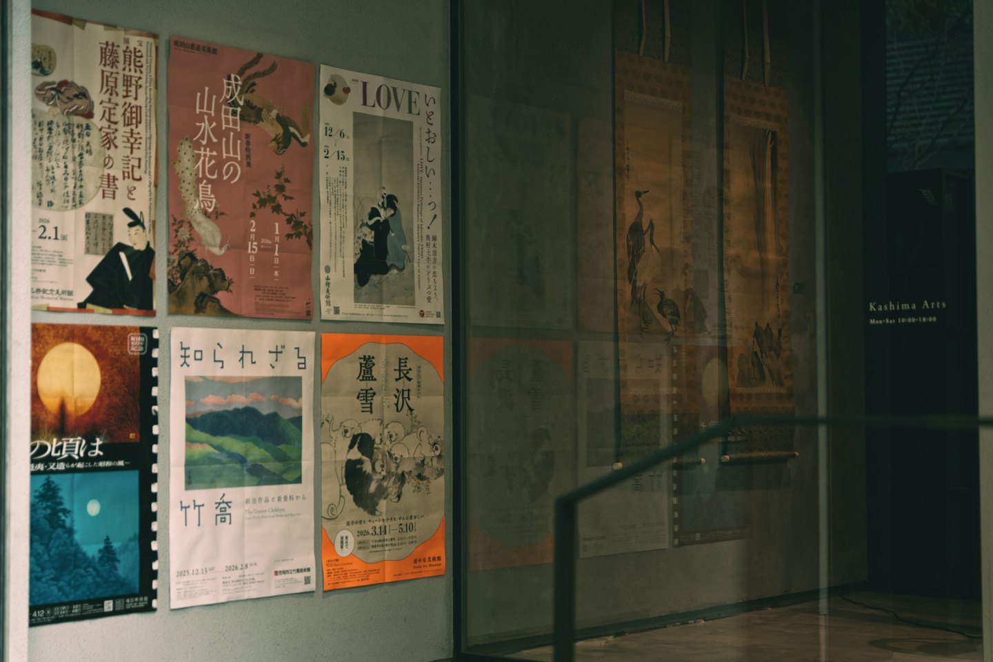 Poster giapponesi esposti dietro una parete di vetro della galleria.